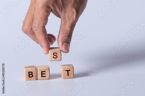hand holding dice with text for illustration of "bet and best" words 