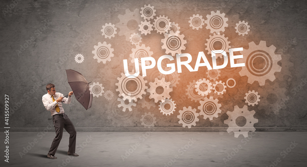 Businessman defending with umbrella from UPGRADE inscription, technology concept