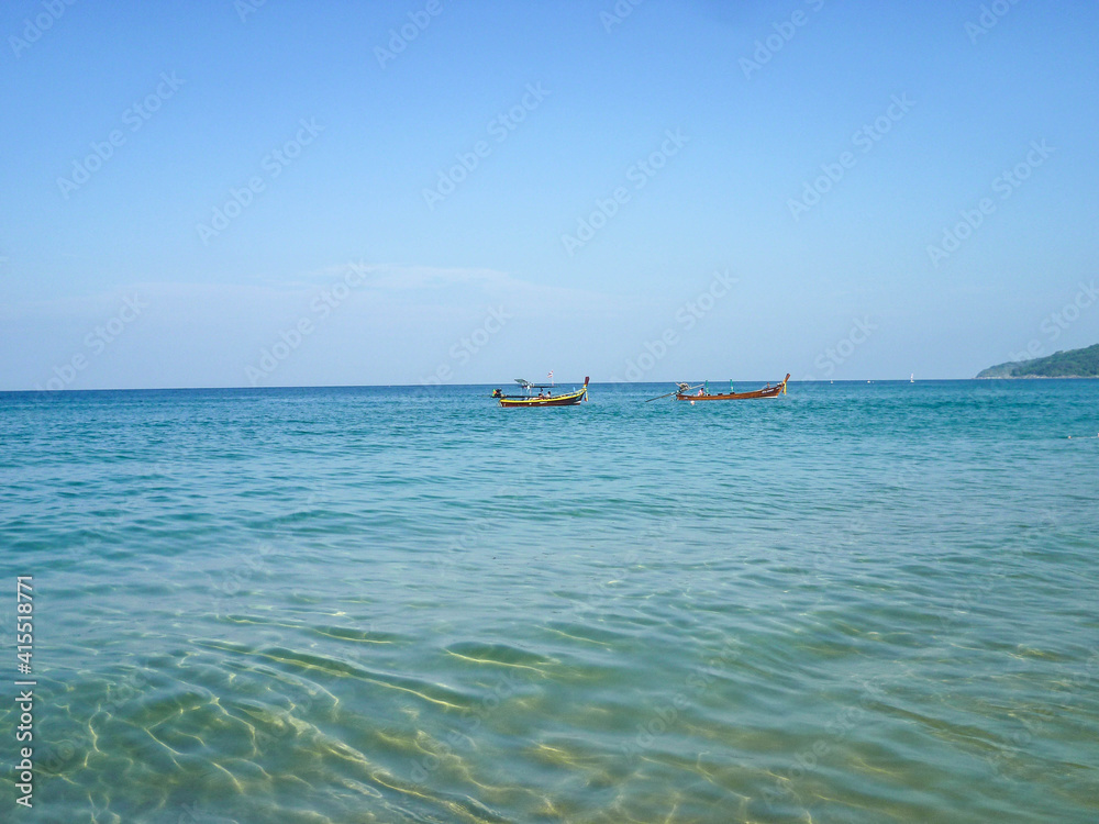 Two wooden boats sail in the Andaman Sea on a sunny summer day.