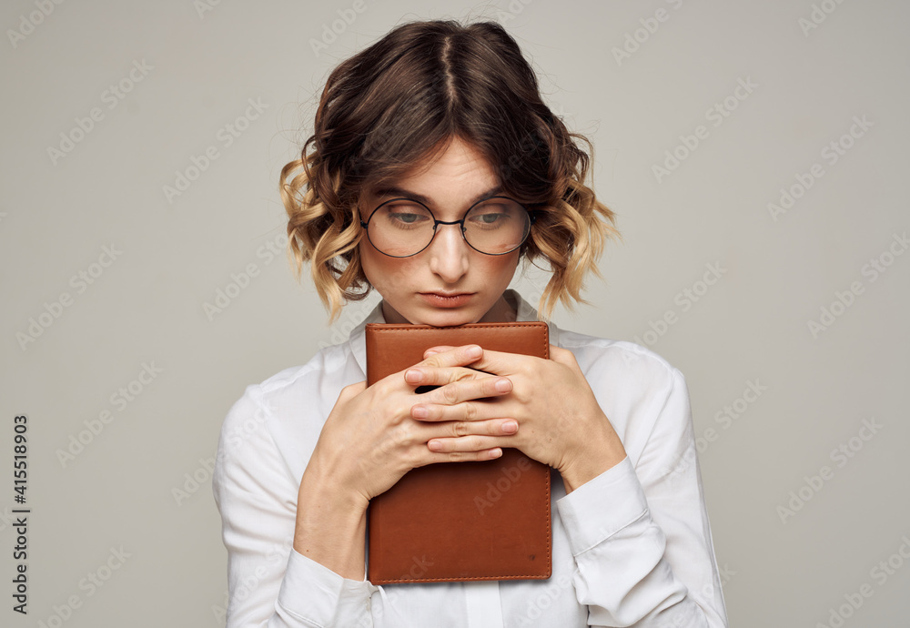 woman on a gray background with a book in her hands and wearing glasses Copy Space