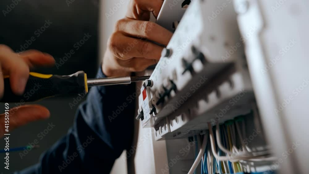 An electrician assembles an electrical panel in an apartment. Electrical box contains many terminals, relays, wires and switches. Manufacture and installation concept concept.