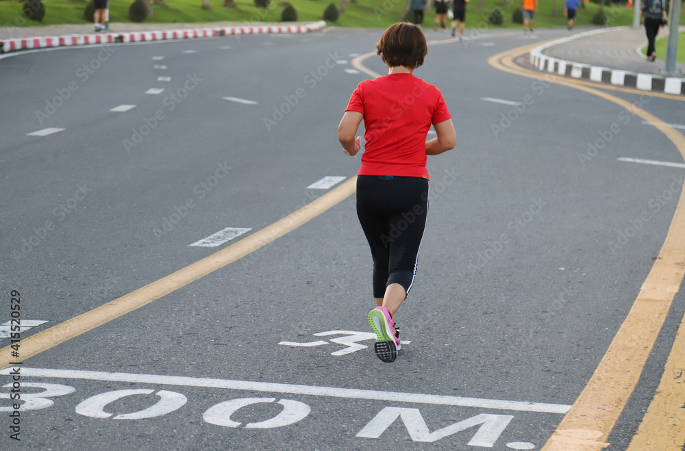 Closeup of young woman jogging on the track in public park.