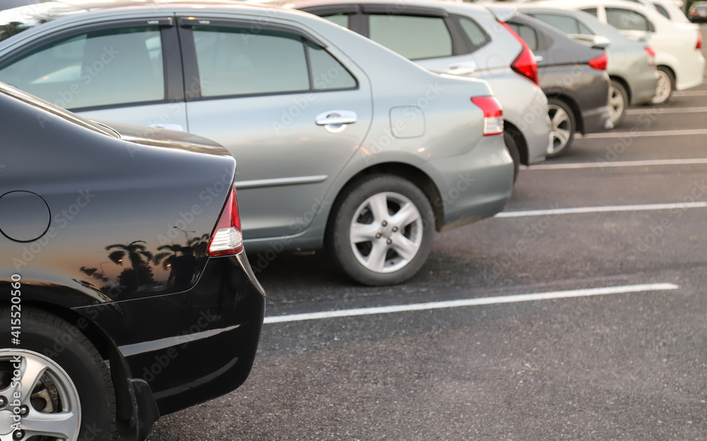 Closeup of rear or back side of black car with  other cars parking in parking area.
