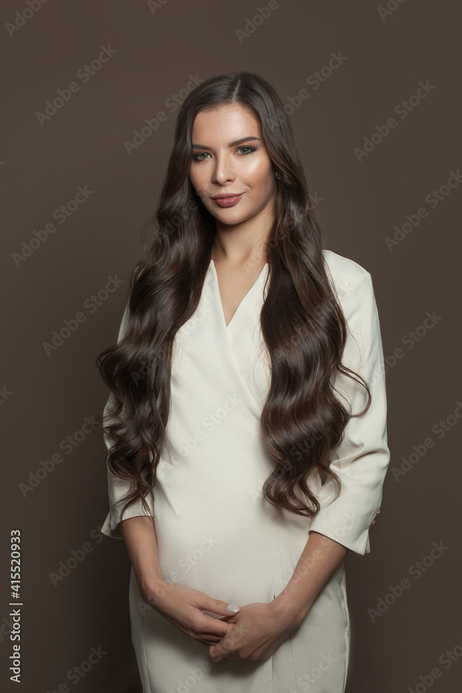 Cheerful young woman with curly hairstyle wearing white dress on brown background Cheerful young woman with curly hairstyle wearing white dress on brown background