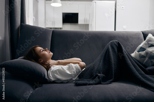 woman covered with a blanket is resting lying on the sofa
