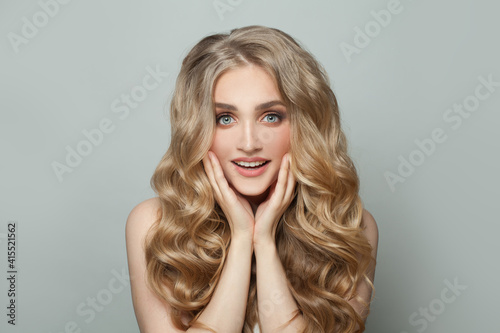 Surprised woman with long perfect curly hair on white background