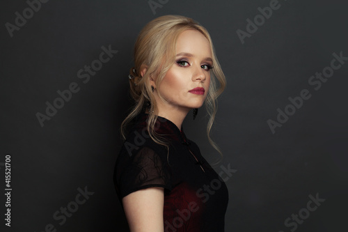 Young blonde woman on black background portrait