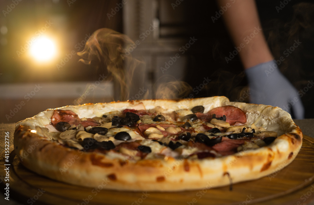 Fresh hot Italian pizza with cheese and steam on the table in a pizzeria. Food delivery.
