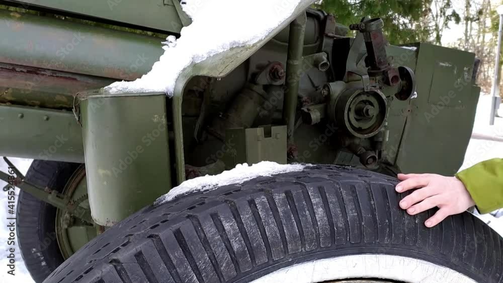 Cannon wheel close up. The teenager's hand touches history. Military equipment. Rodniki town, Russia, winter 2020. Cannon wheel close up. The teenager's hand touches history. Military equipment. Rodniki town, Russia, winter 2020.