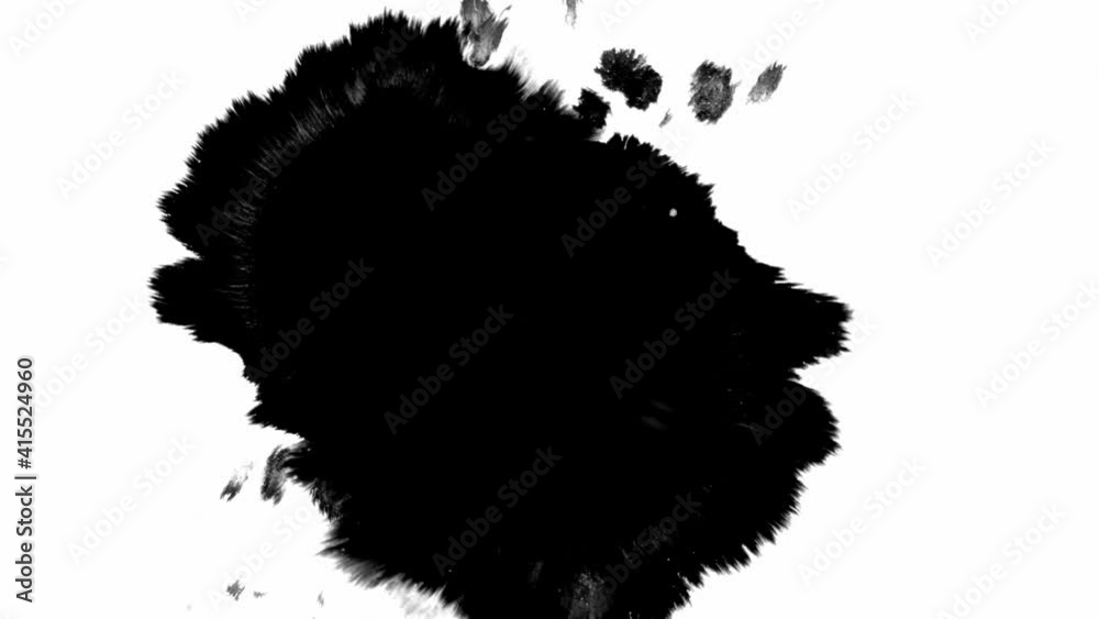 Black ink spills onto white paper, forming beautiful streaks. Beautiful black watercolor ink drops transition