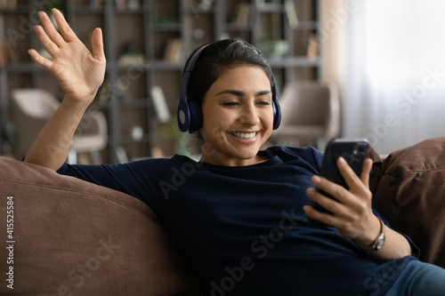 Wallpaper Mural Smiling young Indian woman in headphones look at cellphone screen talk on video call online. Happy ethnic female in earphones have webcam digital conference on smartphone. Virtual event concept. Torontodigital.ca