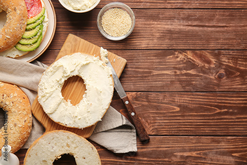 Bagel with tasty cream cheese on wooden background