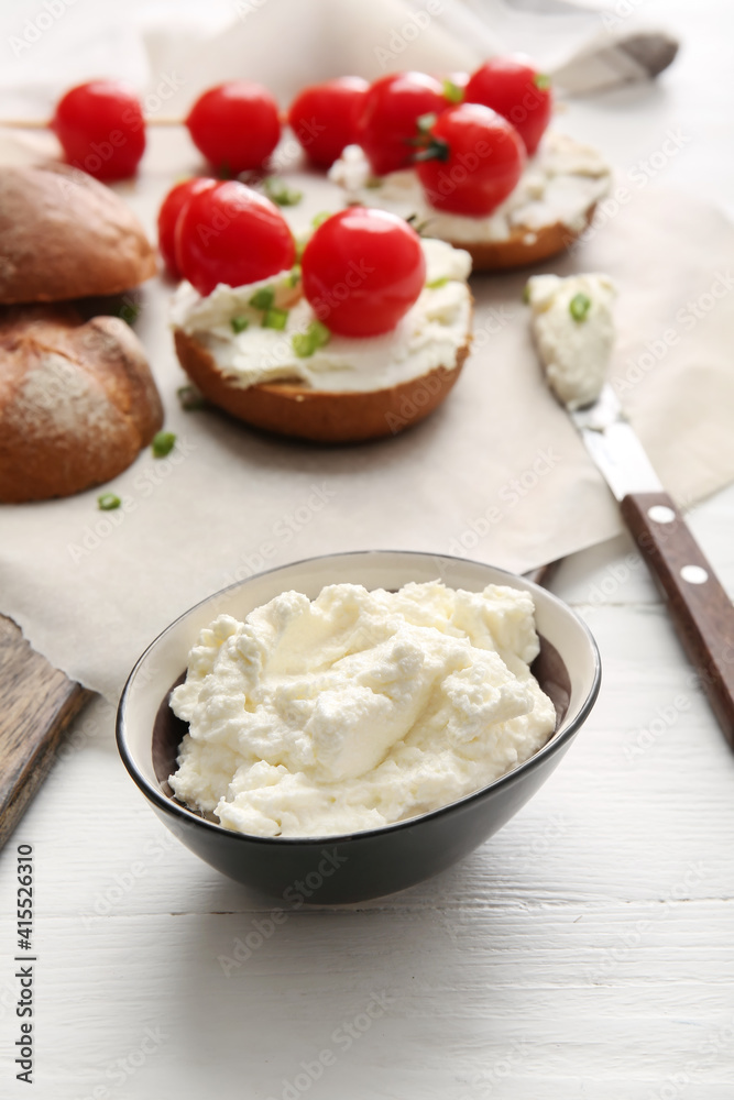 Bowl with tasty cream cheese on light wooden background Bowl with tasty cream cheese on light wooden background