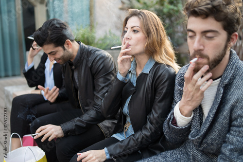 Fotografie Bad habits - group of young friends smoking cigarettes together outdoors