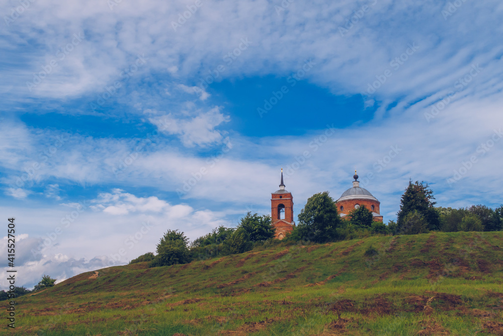 Old Christian orthodox church on the hill during sunny summer day with blue sky and clouds background landscape. Russia