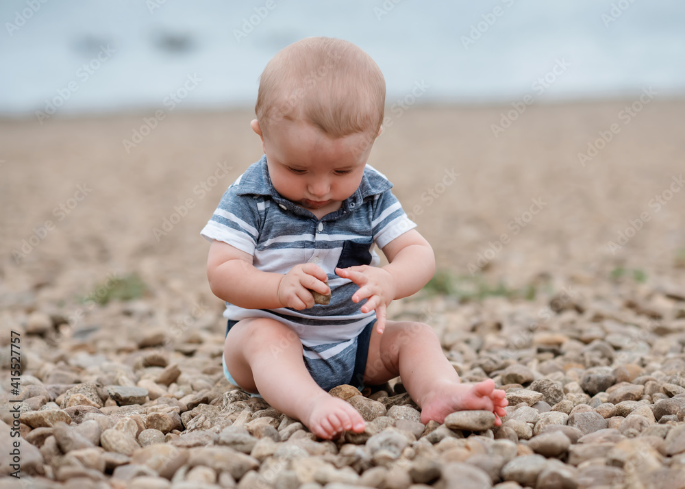 Small boy playing with stones on the seaside Small boy playing with stones on the seaside
