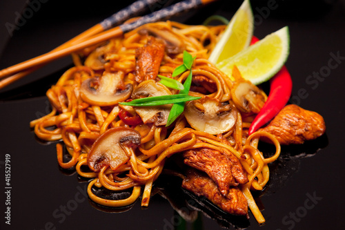 Spicy asian noodles with mushrooms and chicken close up