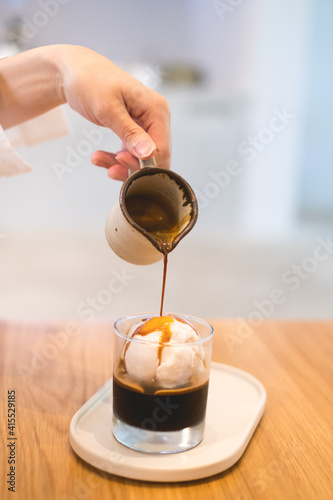 Coffee affogato with vanilla ice cream and espresso. Female hand pouring coffee in the glass with icecream