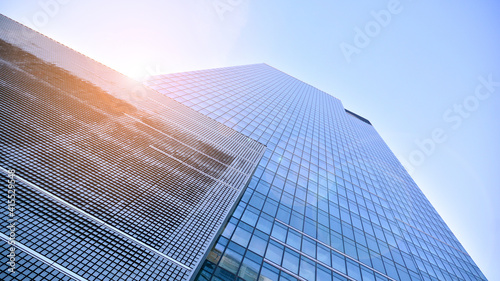 Downtown corporate business district architecture. Glass reflective office buildings against blue sky and sun light. Economy, finances, business activity concept. Rising sun on the horizon.