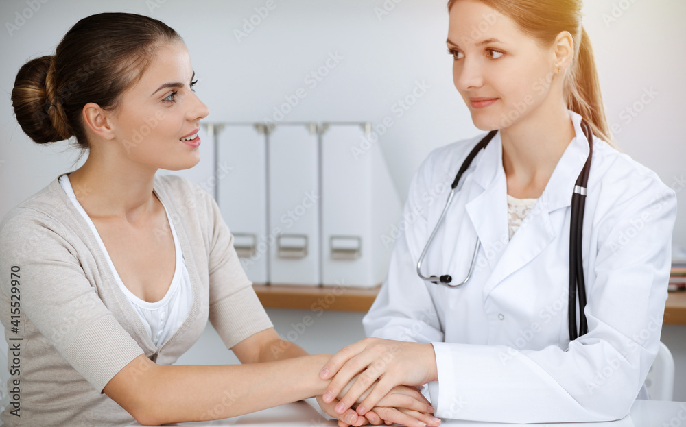 Doctor and patient sitting and discussing health examination results in sunny clinic. Health care, medicine and good news concepts Doctor and patient sitting and discussing health examination results in sunny clinic. Health care, medicine and good news concepts