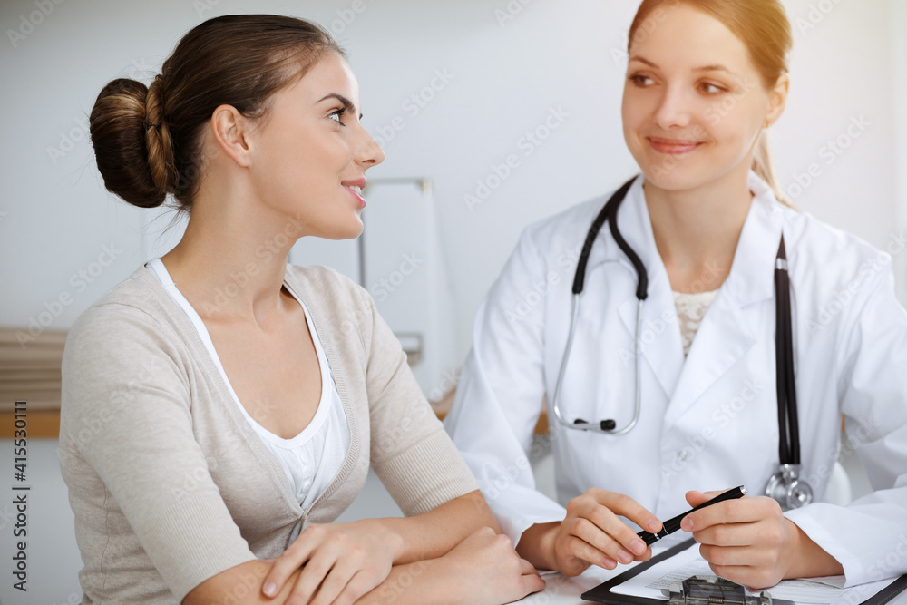 Doctor and patient sitting and discussing health examination results in sunny clinic office Doctor and patient sitting and discussing health examination results in sunny clinic office