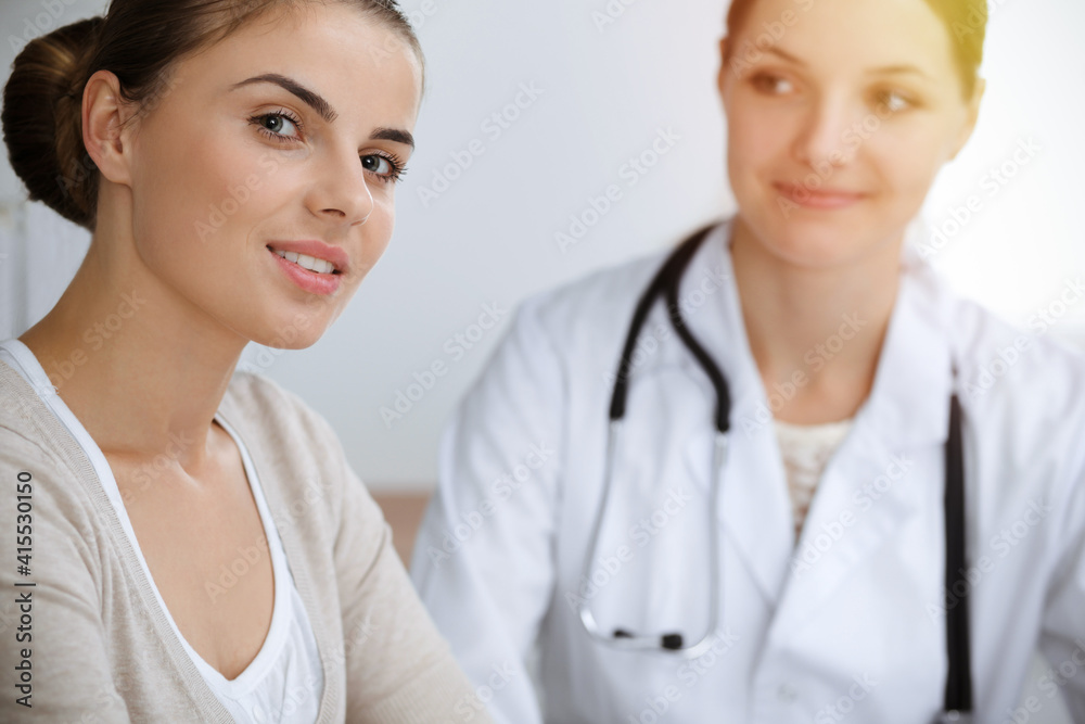 Doctor and patient sitting and discussing health examination results in sunny clinic office Doctor and patient sitting and discussing health examination results in sunny clinic office