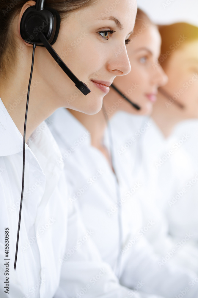 Call center. Beautiful young woman using headset and computer to help customers in sunny office. Business concept Call center. Beautiful young woman using headset and computer to help customers in sunny office. Business concept