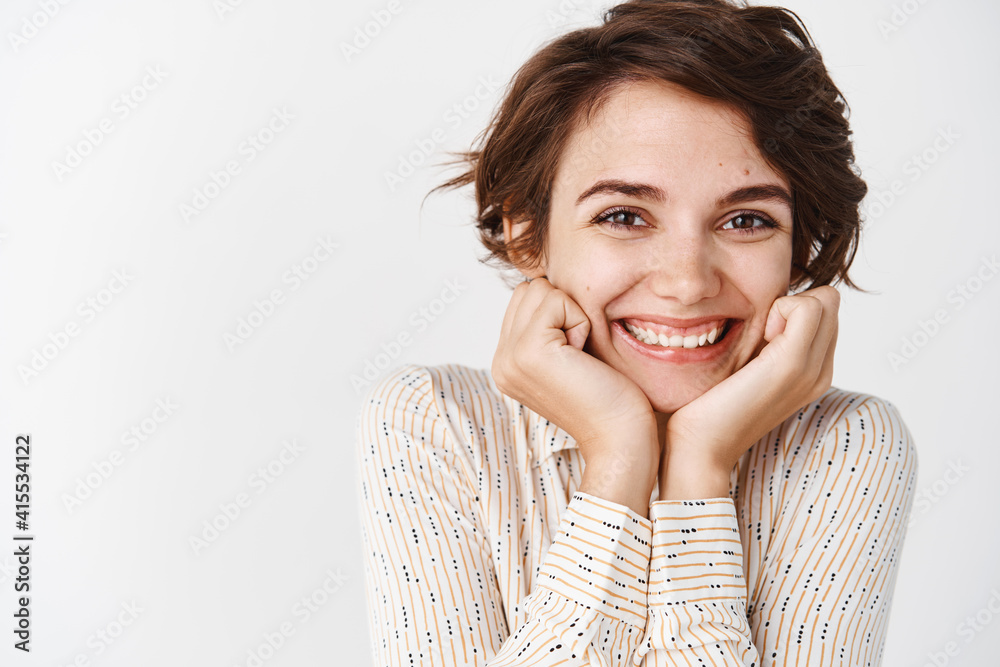 Lovely caucasian woman lean face on hands and smiling happy at camera, standing over white background in casual blouse Lovely caucasian woman lean face on hands and smiling happy at camera, standing over white background in casual blouse