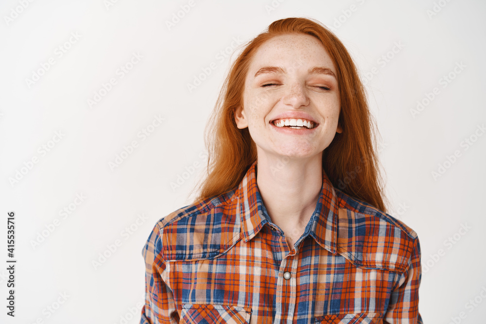 Happy young woman with red hair, close eyes and smiling dreamy, standing over white background Happy young woman with red hair, close eyes and smiling dreamy, standing over white background