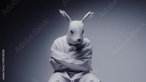 Madness and mental illness concept. Scary, crazy person in animal mask tied in a white room. Nightmare, psychosis. Paranoia and depression concept, isolated madman.