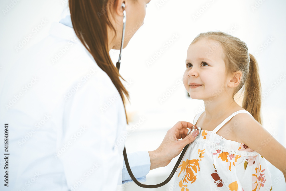 Doctor examining a little girl by stethoscope. Happy smiling child patient at usual medical inspection. Medicine and healthcare concepts Doctor examining a little girl by stethoscope. Happy smiling child patient at usual medical inspection. Medicine and healthcare concepts