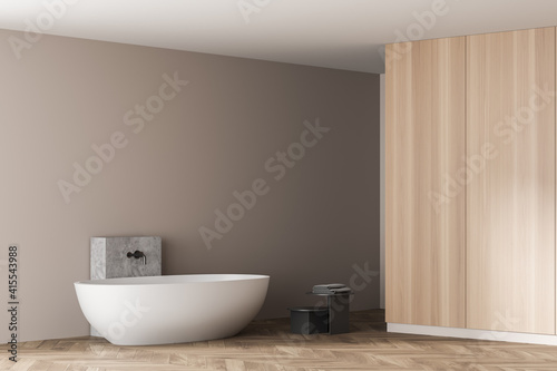 Wooden bathroom with white bathtub and towels near drawer