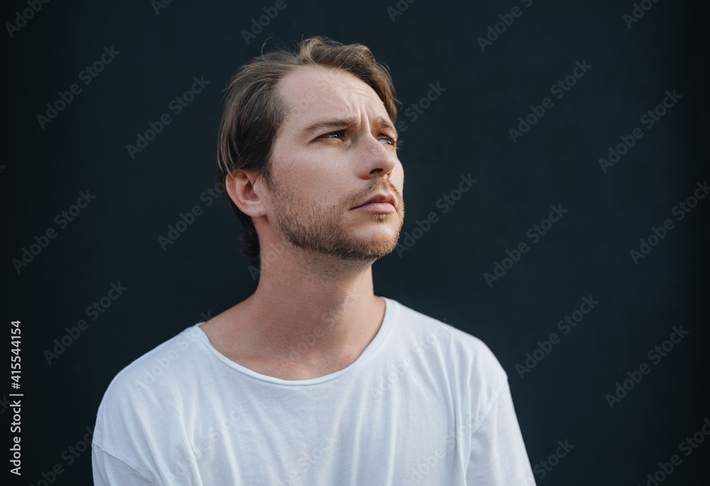 Portrait of european man in white t-shirt at dark wall