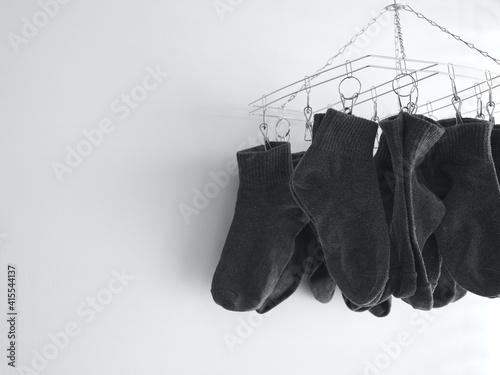 Gray socks are dried on, Stainless steel hanging rack indoor on white background with copy space, Washing socks with detergent for cleanliness and hygiene. © Apisit