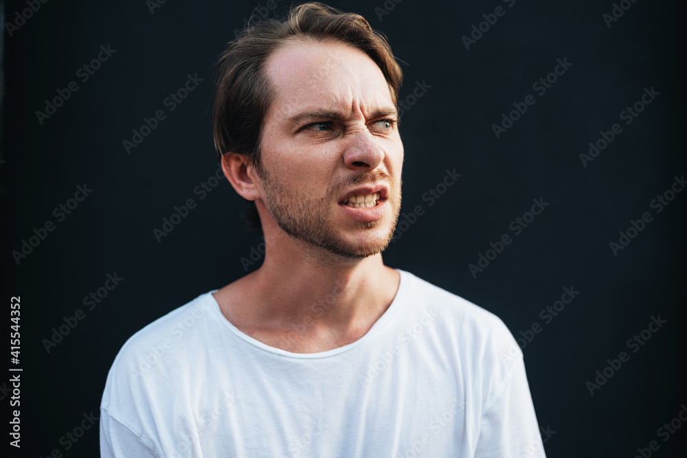 Angry man clenched his teeth in anger at dark wall