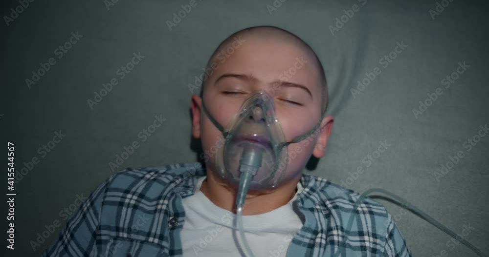 Top view of sick unconscious kid with oxygen mask in ambulance car