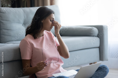 Tired eyes. Fatigued arab female freelancer overworked by pc take glasses off rub nose feel eye strain pain. Young indian woman has vision problem after spending too much time before computer screen photo