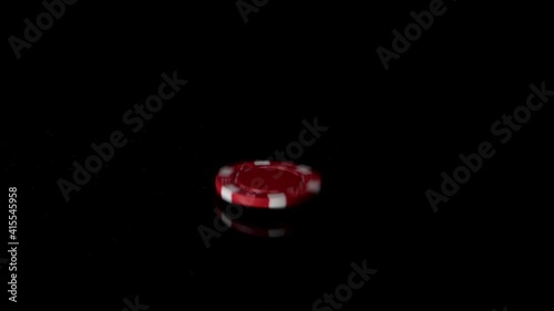 Solo red poker chip falling in sow motion on reflective black backdrop