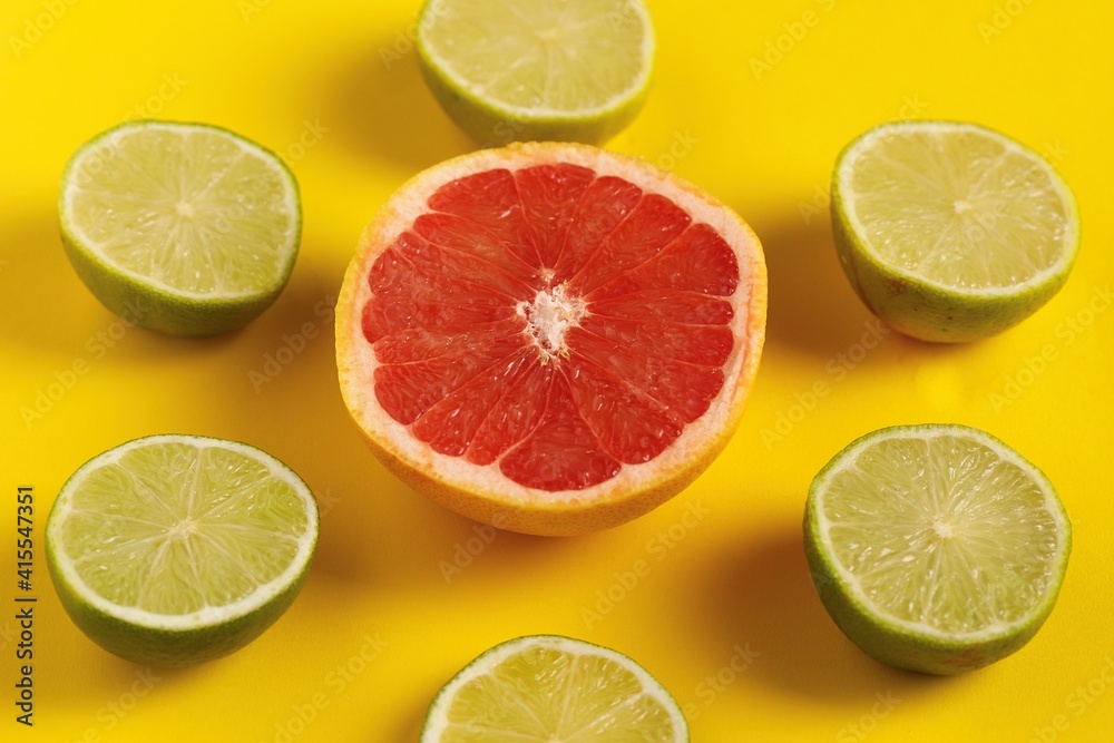 Fototapeta premium Limas alrededor de un pomelo con fondo amarillo