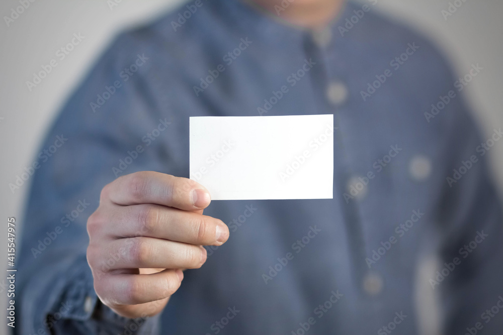 A man holds a white business card. A paper in the hands of a man. Prepared for your text. Isolated on a gray background A man holds a white business card. A paper in the hands of a man. Prepared for your text. Isolated on a gray background