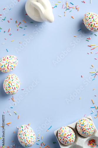Photography Easter frame made of colorful eggs bunny, sweets on pastel blue background