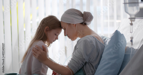 Cuadro en lienzo Side view of young woman with cancer sitting on hospital bed with little daughte