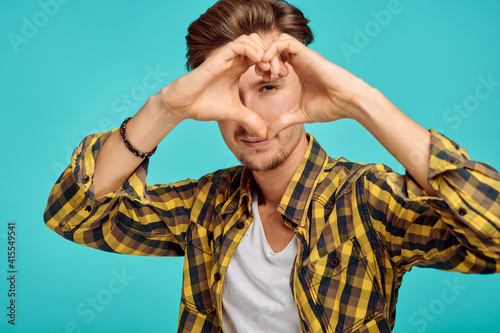 Photos Young man shows heart sign, blue background