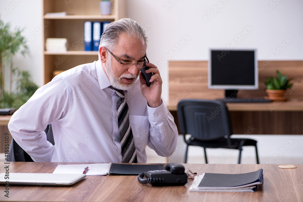 Old male employee suffering from radiculitis at workplace Old male employee suffering from radiculitis at workplace