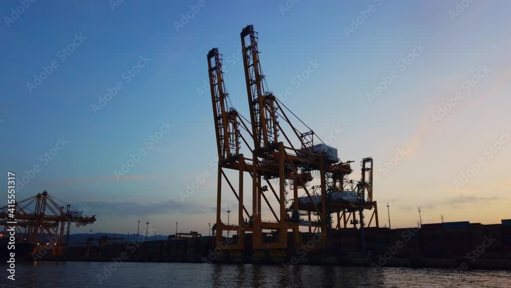 Import-Export shipping concept: Camera moving around two close up black crane silhouettes standing still at the port. Clear morning sky. Industrial sea background with copy space in 4k. Import-Export shipping concept: Camera moving around two close up black crane silhouettes standing still at the port. Clear morning sky. Industrial sea background with copy space in 4k.