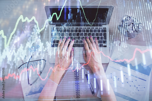 Double exposure of woman hands working on computer and forex graph hologram drawing. Top View. Financial analysis concept.