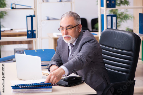 Old male employee and paperwork in the office