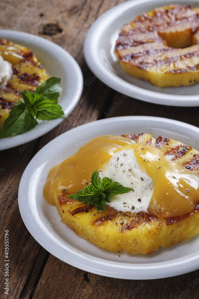 Vanilla ice cream with black pepper, fruit topping and grilled pineapple. Dessert is decorated with a fresh mint leaf. Festive menu Vanilla ice cream with black pepper, fruit topping and grilled pineapple. Dessert is decorated with a fresh mint leaf. Festive menu