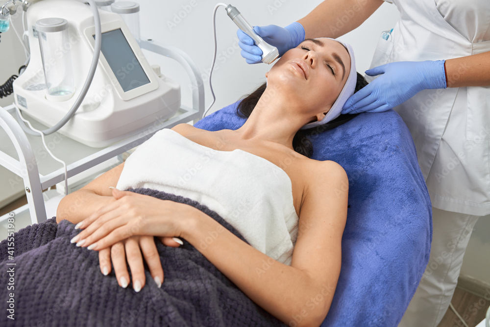 Obraz premium Professional cosmetologist is doing procedures for client in light cabinet