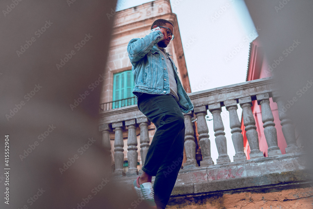 black boy walking on ladder using mobile phone